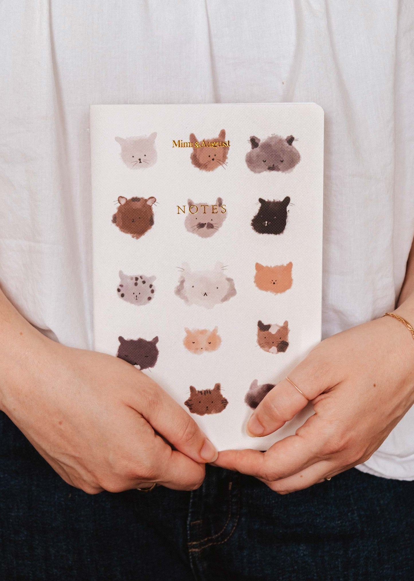 Notebook with animal illustrations held by a person wearing a white shirt.
