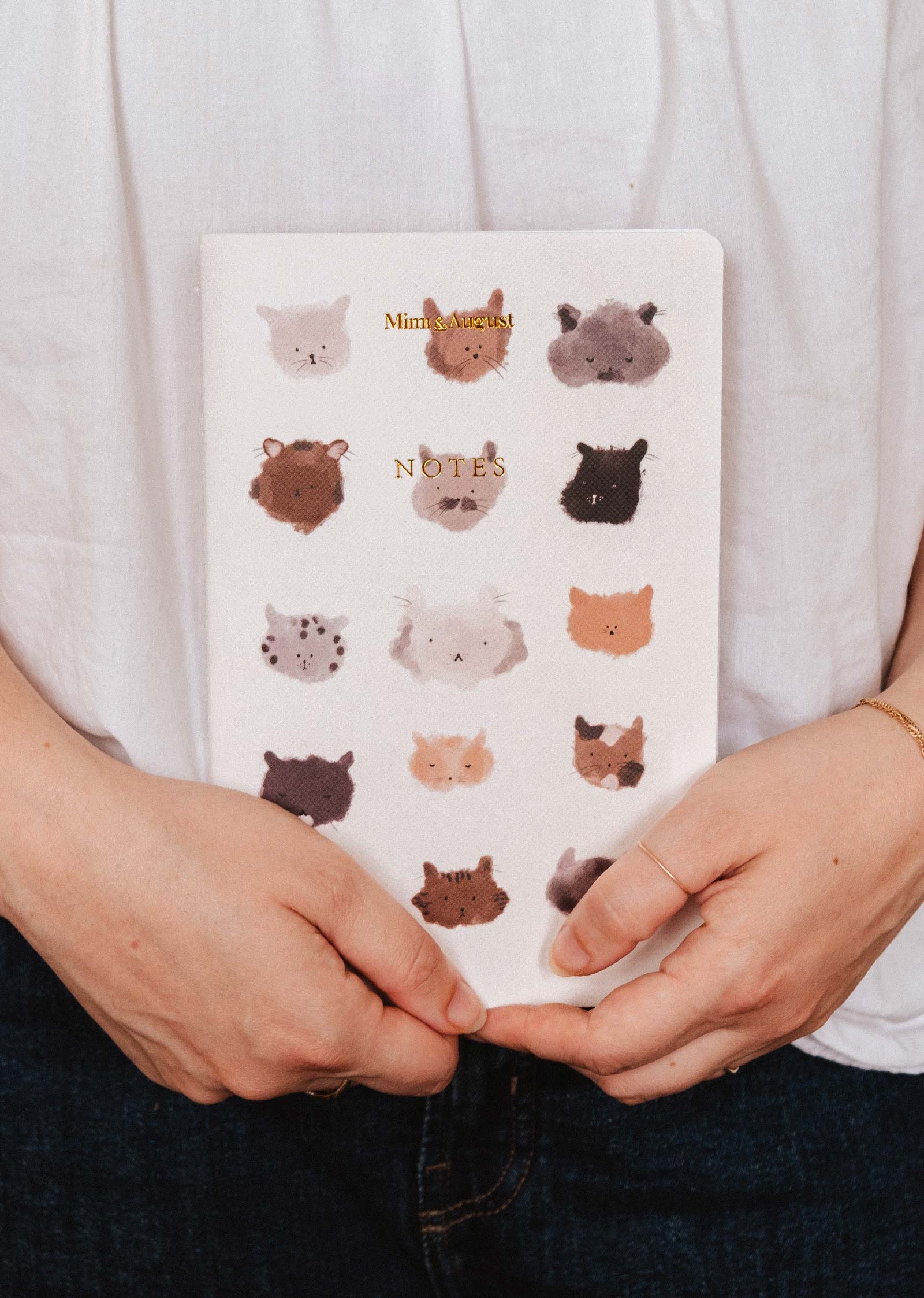 Notebook with animal illustrations held by a person wearing a white shirt.