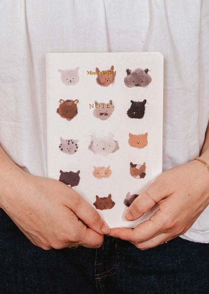 Notebook with animal illustrations held by a person wearing a white shirt.