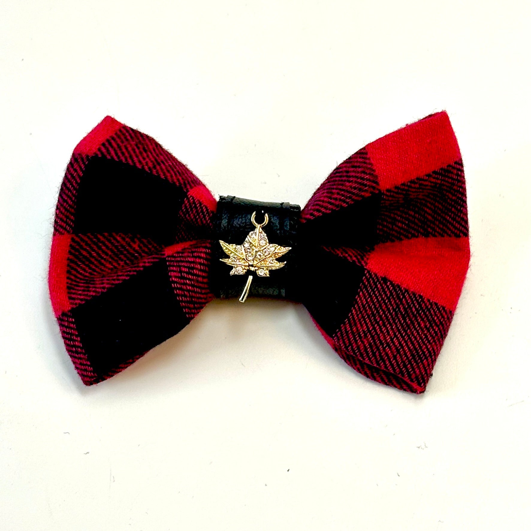 Red and black plaid bow tie with a gold leaf charm on a white background