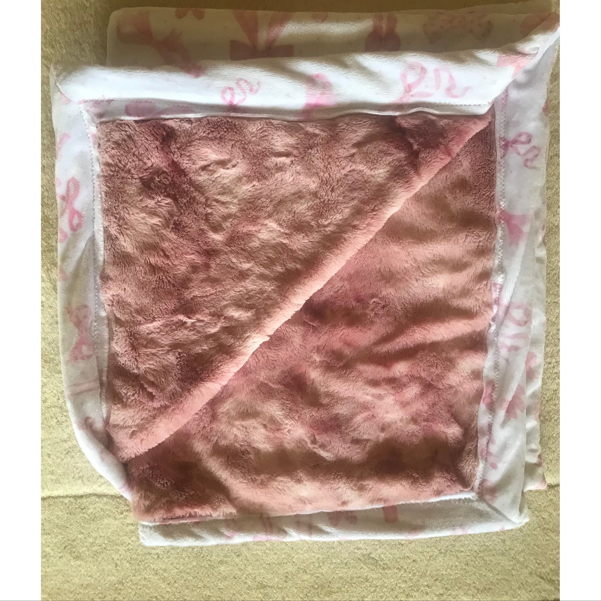 Pink blanket with floral pattern on a beige surface