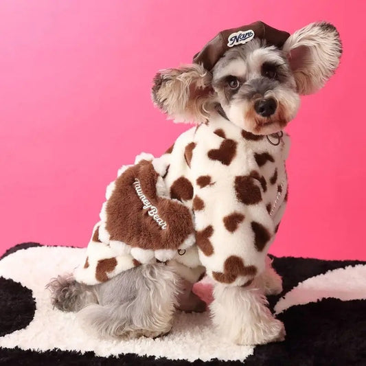 Dog wearing a cow print outfit with a pink background