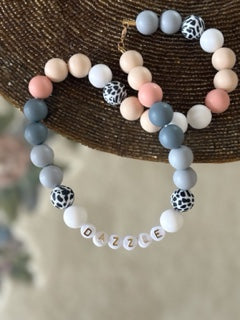 Silicone pet necklace with letter beads on a woven surface
