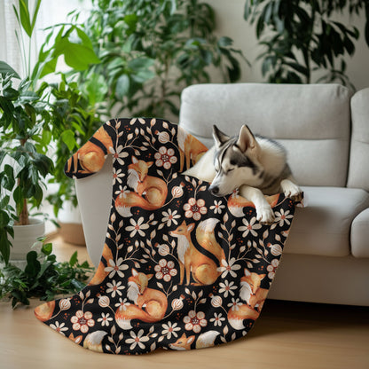 Dog lying on a floral-patterned blanket with foxes and flowers, surrounded by plants and a couch.