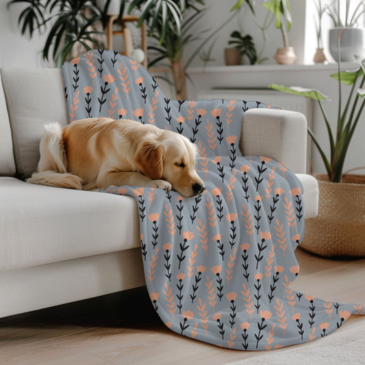 Dog lying on a floral-patterned blanket draped over a couch in a cozy living room.