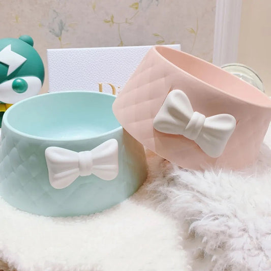 Two pet bowls with bow decorations on a soft surface